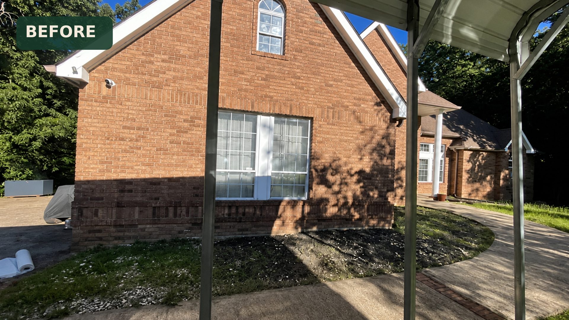 Overgrown flower beds and weeds along the left side of a brick home in Chattanooga, TN before LNK Ventures landscaping