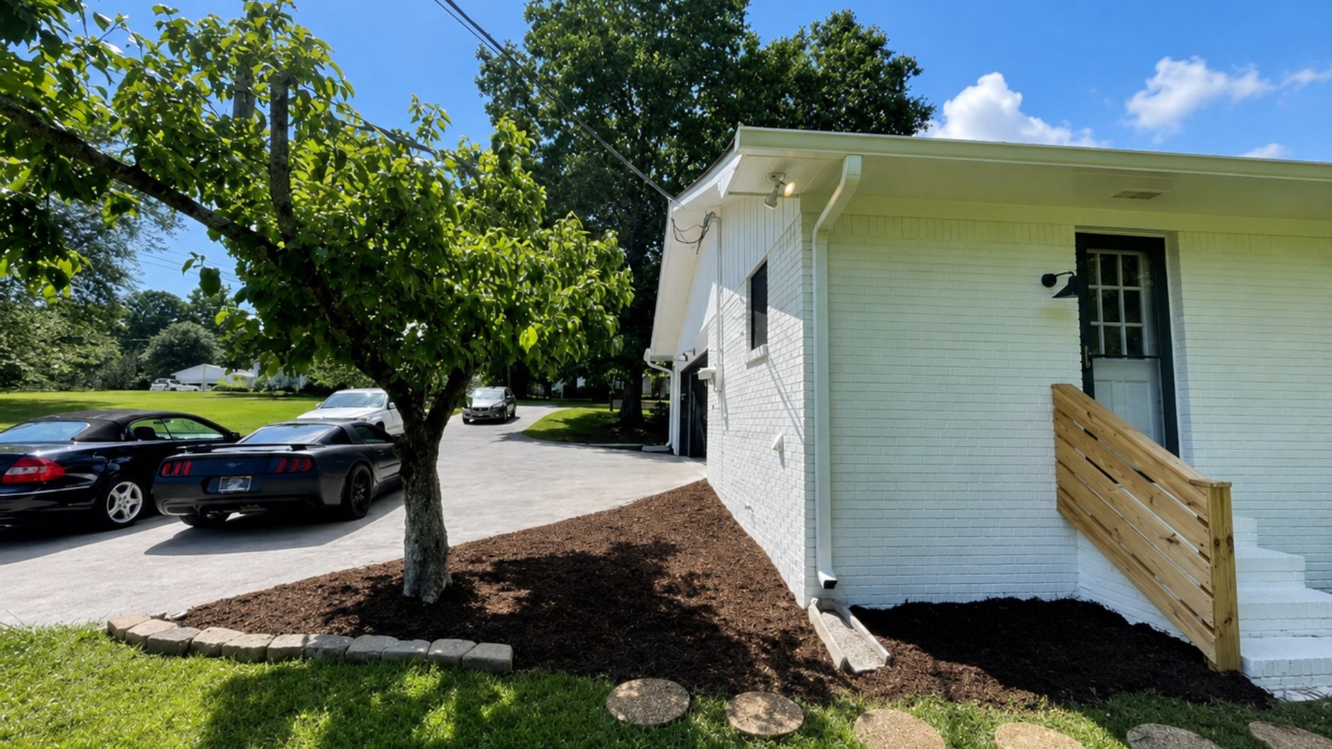 Side yard at a white ranch home in Chattanooga, TN with edged bed, fresh mulch, and manicured lawn by LNK Ventures