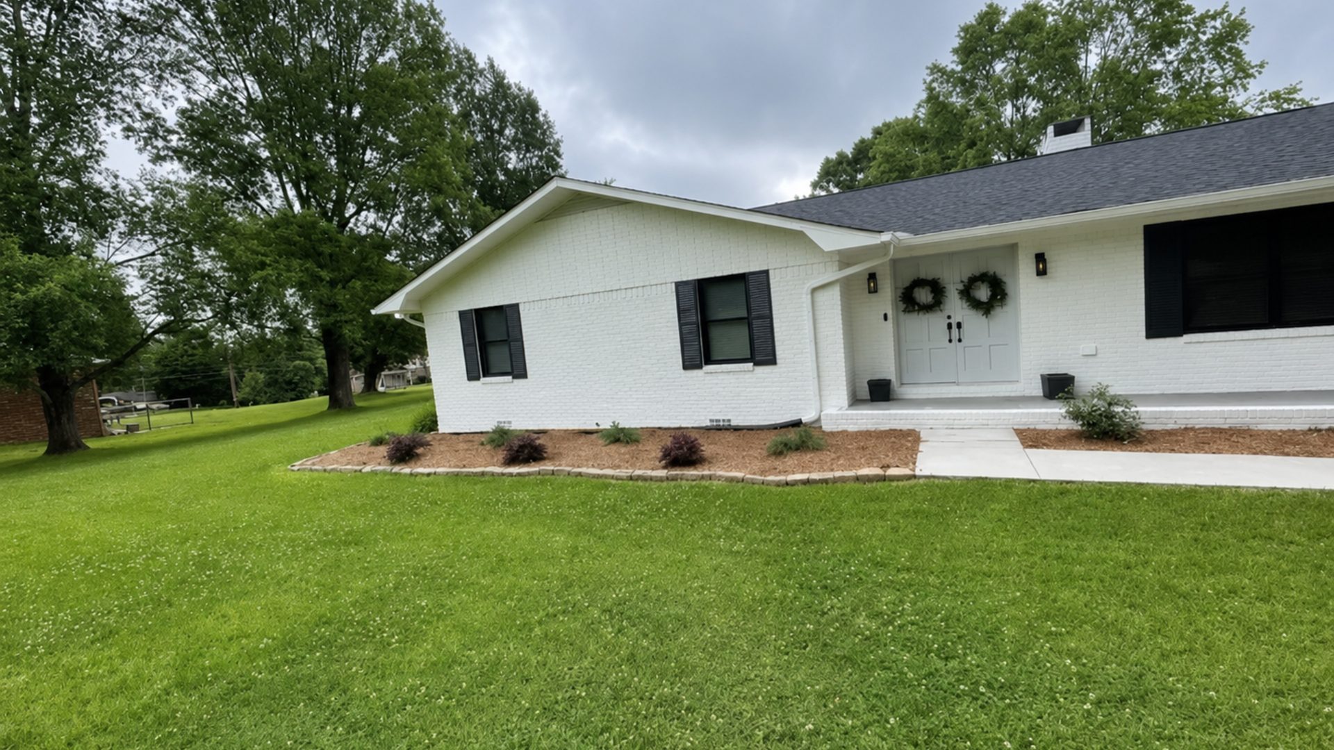 Left elevation of a white ranch home in Chattanooga, TN showing tidy foundation planting by LNK Ventures