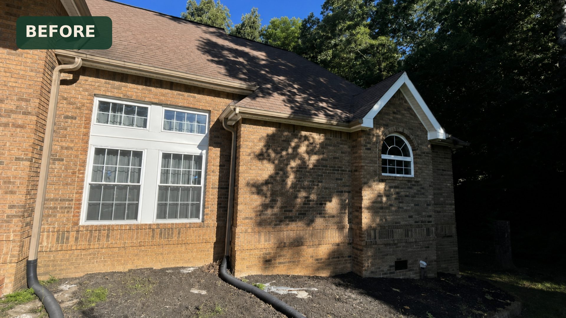 Neglected landscaping and bare mulch beds beside a brick home in Chattanooga, TN before service