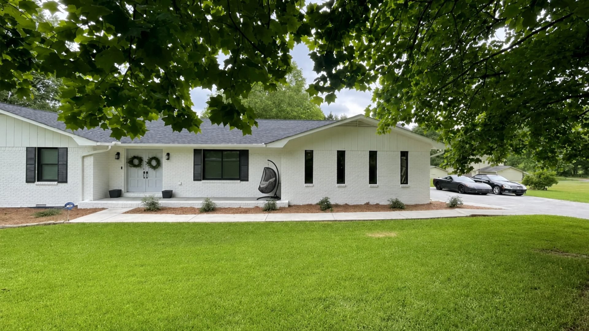 Front elevation of a painted-brick ranch home in Chattanooga, TN with foundation beds by LNK Ventures