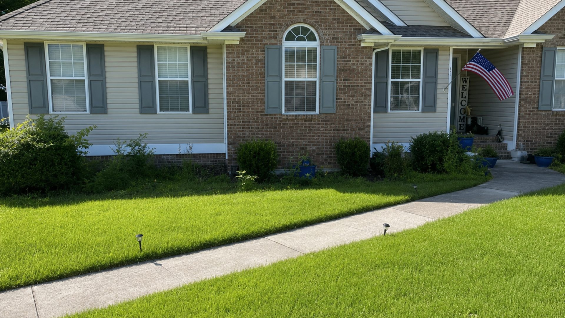 Wide shot of a brick home in Chattanooga, TN with tightly trimmed hedges and tidy landscaping by LNK Ventures
