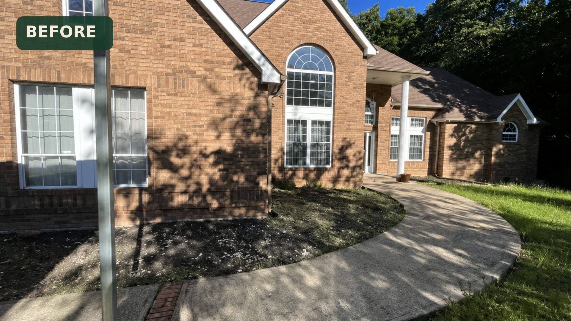 Wide view of tired front yard landscaping at a brick home in Chattanooga, TN before LNK Ventures crew arrived