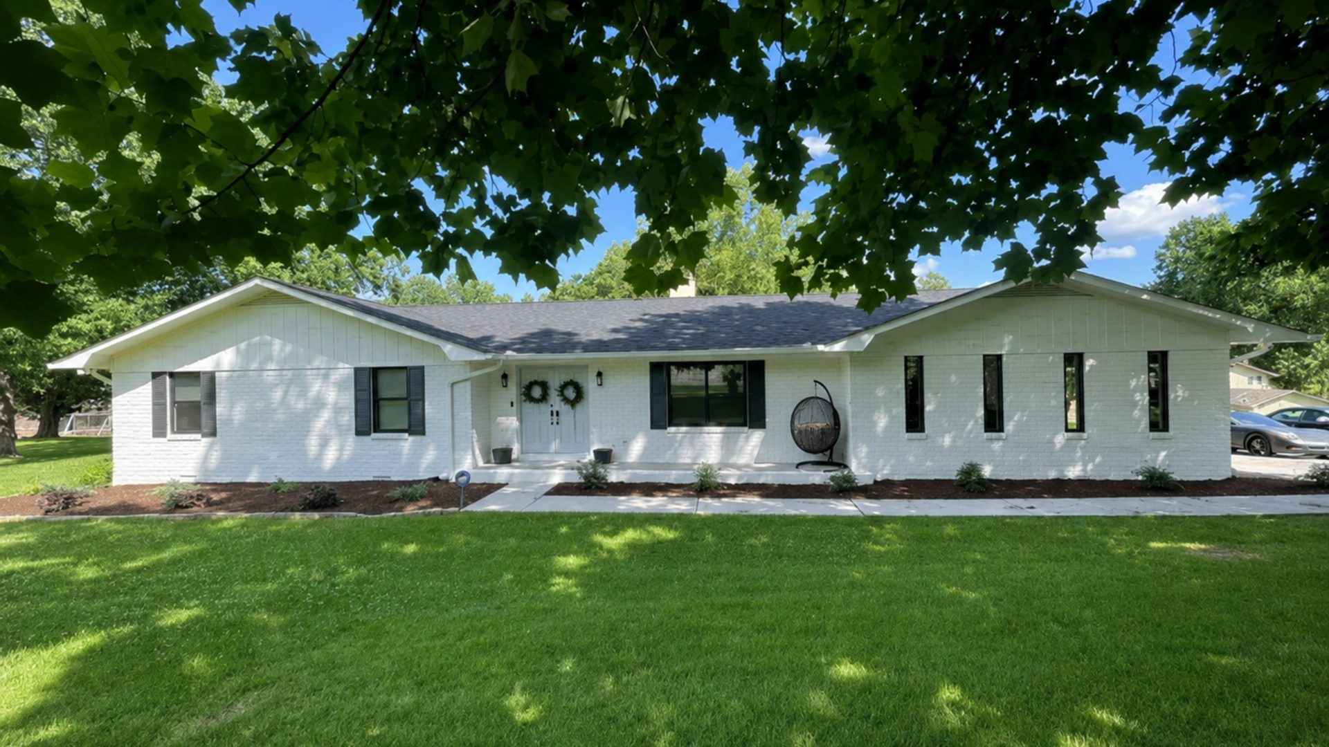 Wide front-lawn view of a white ranch home in Chattanooga, TN with crisp foundation beds, fresh mulch, and clean curb appeal by LNK Ventures