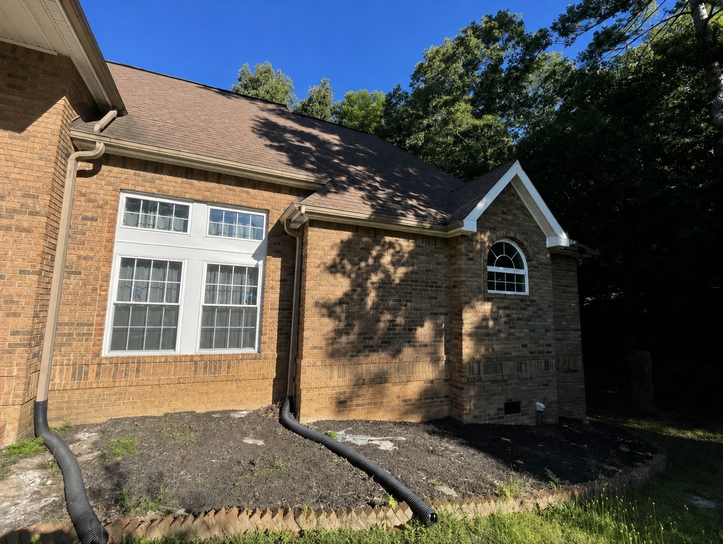 Drainage tubing being installed along the foundation of a brick home in Chattanooga, TN during LNK Ventures landscape restoration