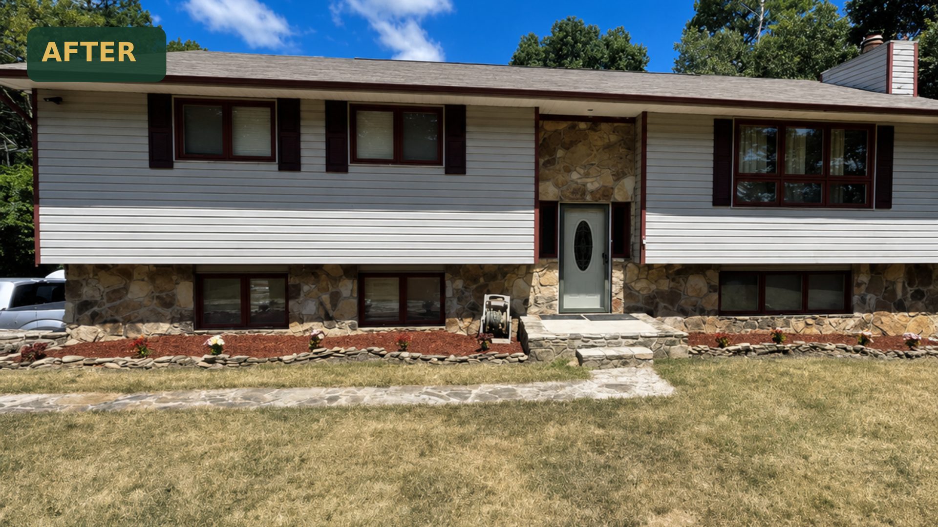 Wide after shot of a split-level home in Chattanooga, TN with new red mulch beds, stone borders, and revitalized lawn by LNK Ventures