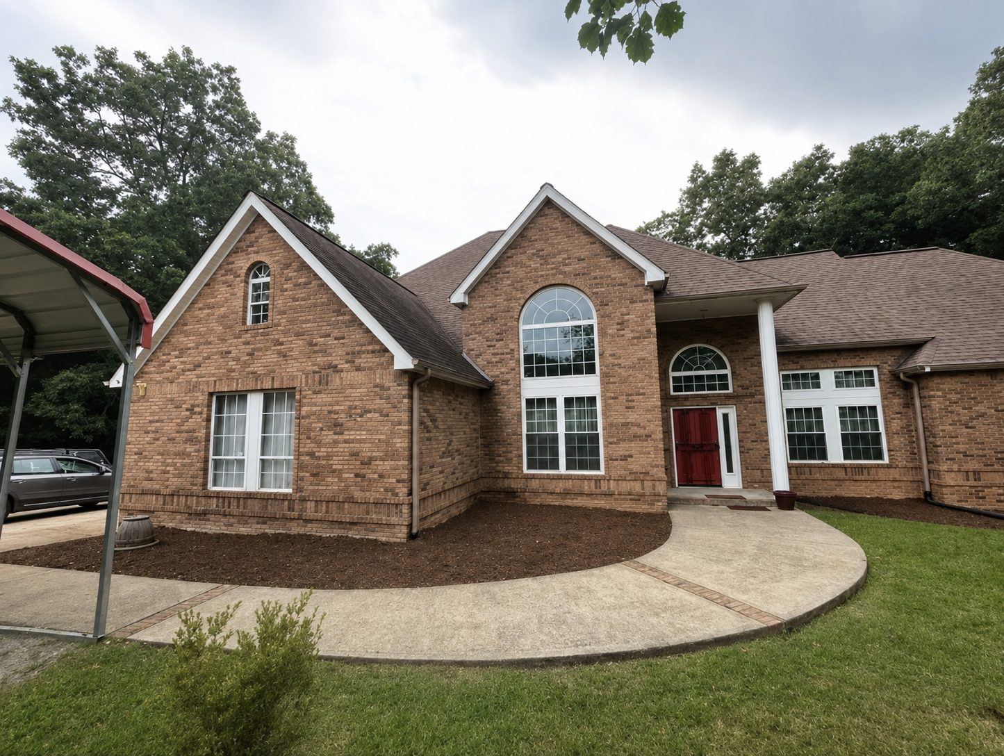 Front elevation of a Chattanooga, TN brick split-level home with a curved walkway and freshly mulched beds by LNK Ventures